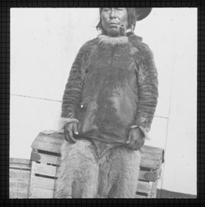 Image of Inuit man with pipe, aboard by crate